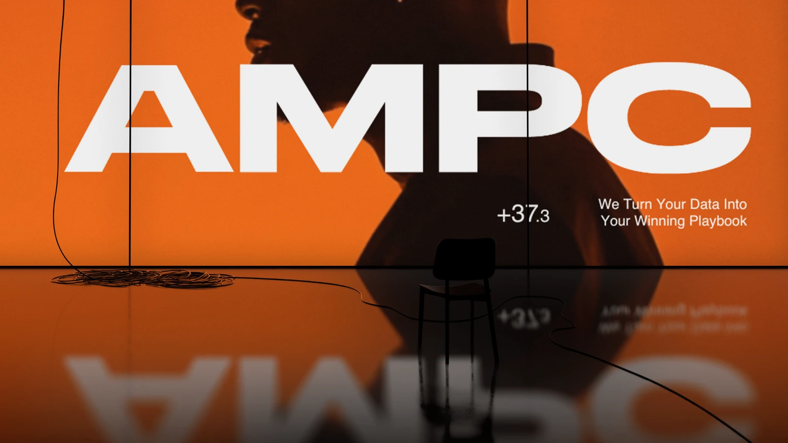 AMPC's white wordmark across an orange venue screen with a synthetic portrait and reflective floor